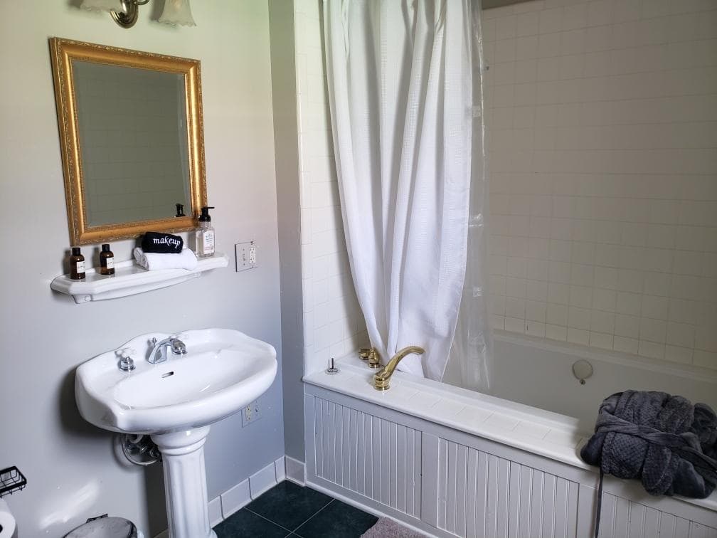 Pedestal sink, gilded mirror and tub in the Melville Suite bathroom