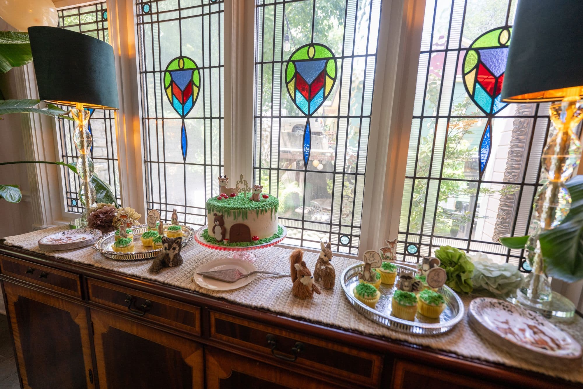 Celebration cake and cupcakes on a sideboard before stained glass windows