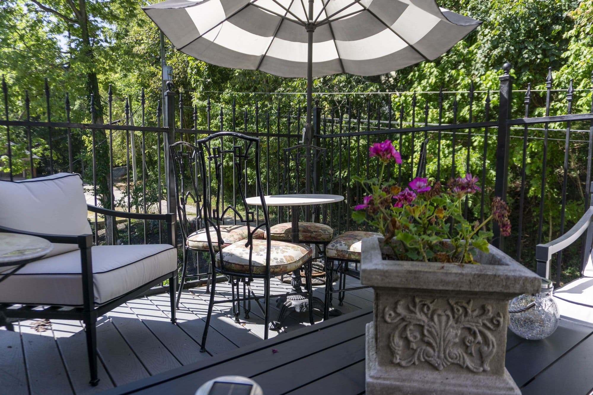 Private balcony with a bistro table and striped umbrella among the trees