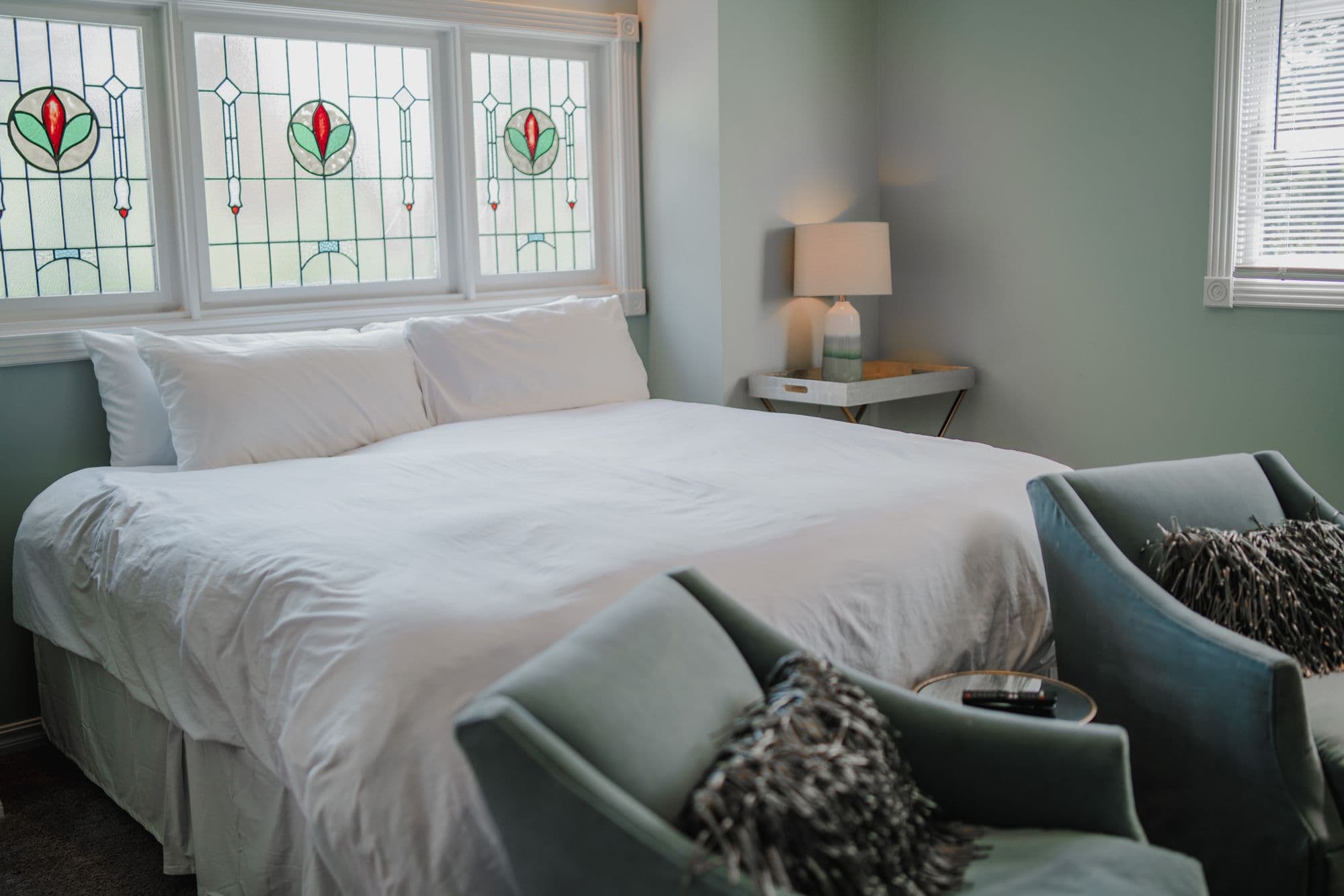 King bed beneath stained glass windows in one of the inn suites