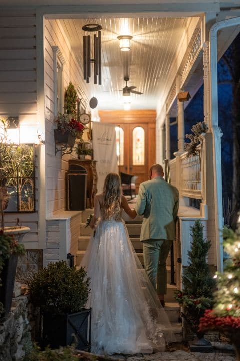 Bride and groom walking up the lantern-lit porch steps of the inn at night